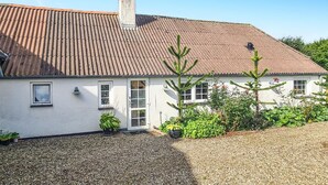 A white house with a tiled roof, a chimney, and a gravel driveway.