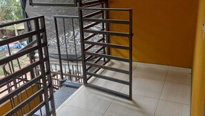A room with a metal gate leading to an outdoor area, a tiled floor, and a yellow wall.