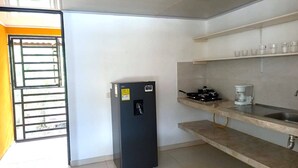 A compact kitchen with a refrigerator, a coffee maker, and a sink.