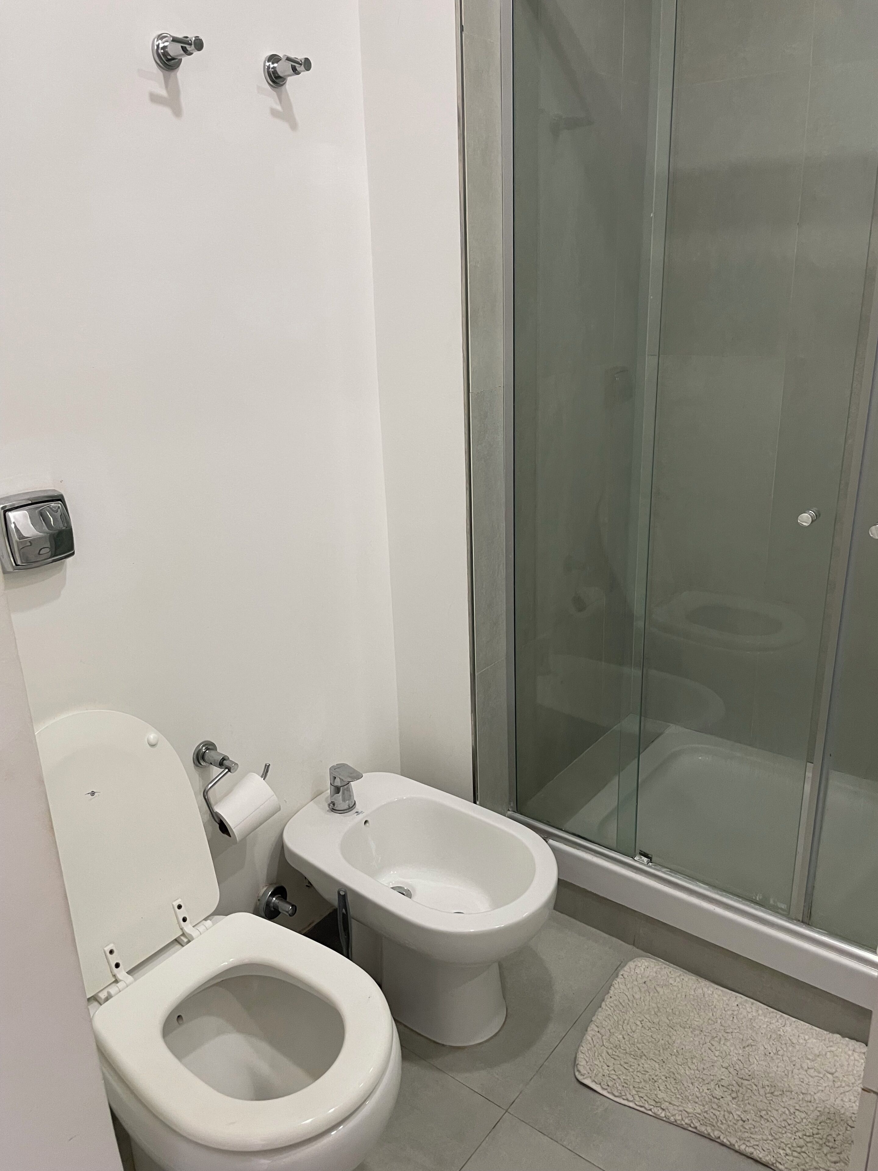 Et badeværelse med toilet, bidet og brusekabine i glas.