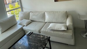 Un soggiorno moderno con un divano bianco, un tavolino da caffè in marmo e un quadro raffigurante una spiaggia.