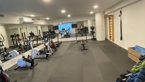 Una palestra con diverse attrezzature per l'allenamento, uno specchio e una scala di legno.