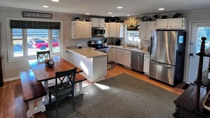 Una cocina moderna con armarios blancos, electrodomésticos de acero inoxidable y una isla central.