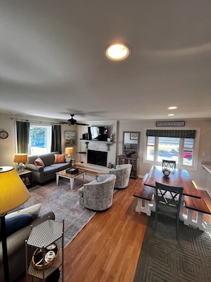 A living room with a fireplace, a dining table, and a TV. - 2 Step - Beachside 3BR/3BA in Emerald Isle, NC (Emerald Isle)