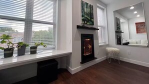 Una sala de estar moderna con chimenea, ventanas amplias y un espejo.