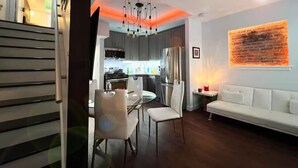 Una cocina moderna con comedor, un sofá blanco y una pared de ladrillo decorativa.