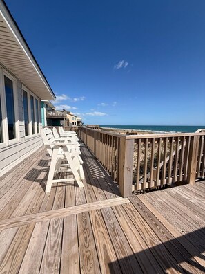 A wooden deck with a view of the ocean, a pool, and a building with a balcony. - Oceanfront 4BR Retreat with Private Beach Access-Discounted for weeks of 6/7 & 6 (Emerald Isle)