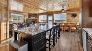 Een ruime keuken met een groot eiland, houten plafond en een open haard.
