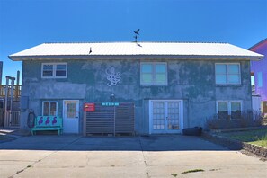 A building with a metal roof, a garage door, and a bench with flamingo decorations. - Spacious Oceanfront Retreat with Private Pool and Hot Tub (Emerald Isle)