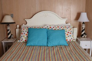 A bed with a polka dot and striped bedspread, two pillows, and two bedside lamps with decorative bases. - Spacious Oceanfront Retreat with Private Pool and Hot Tub (Emerald Isle)