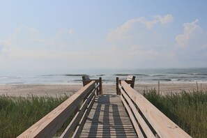 A wooden boardwalk leading to a beach with waves and a clear sky. - Spacious Oceanfront Retreat with Private Pool and Hot Tub (Emerald Isle)