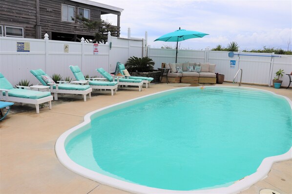 A swimming pool with lounge chairs, a small table, and a sofa. - Spacious Oceanfront Retreat with Private Pool and Hot Tub (Emerald Isle)