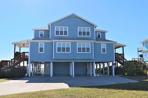 A two-story house with a garage, a covered porch, and a wooden staircase. - 4BR Coastal Retreat with Decks & Grill (Emerald Isle)