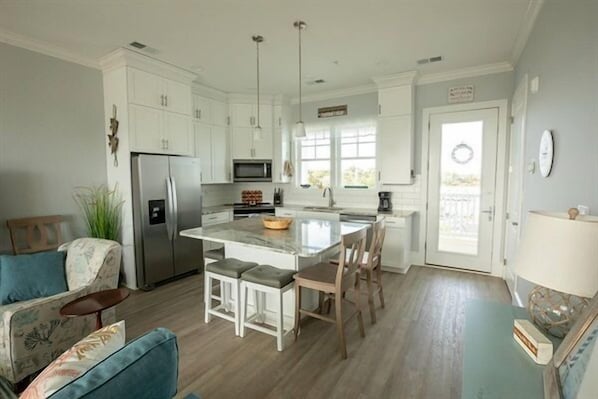 A modern kitchen with white cabinets, a central island, and a dining area with bar stools.