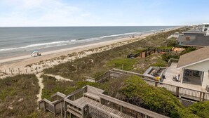 A beach view with a wooden deck, a covered seating area, and a sandy beach. - 4 BD| 4.5 Bath| Luxury Oceanfront Escape-Discounted week of 8/15 (Emerald Isle)