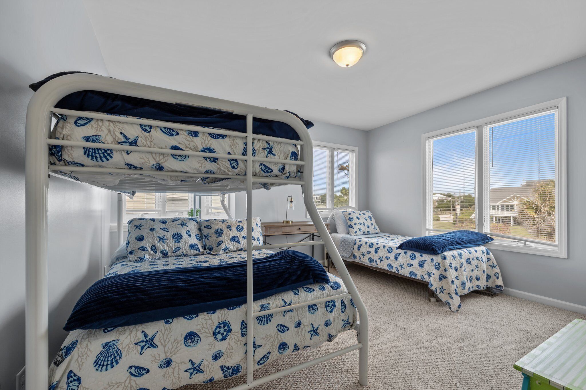 A room with bunk beds, a desk, and a window with a view.