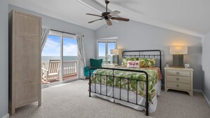 A bedroom with a bed, a nightstand, a ceiling fan, a window with a view, and a door. - 4 BD| 4.5 Bath| Luxury Oceanfront Escape-Discounted week of 8/15 (Emerald Isle)