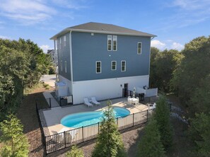 Un bâtiment à deux étages doté d’une piscine, entouré d’une clôture et d’arbres.