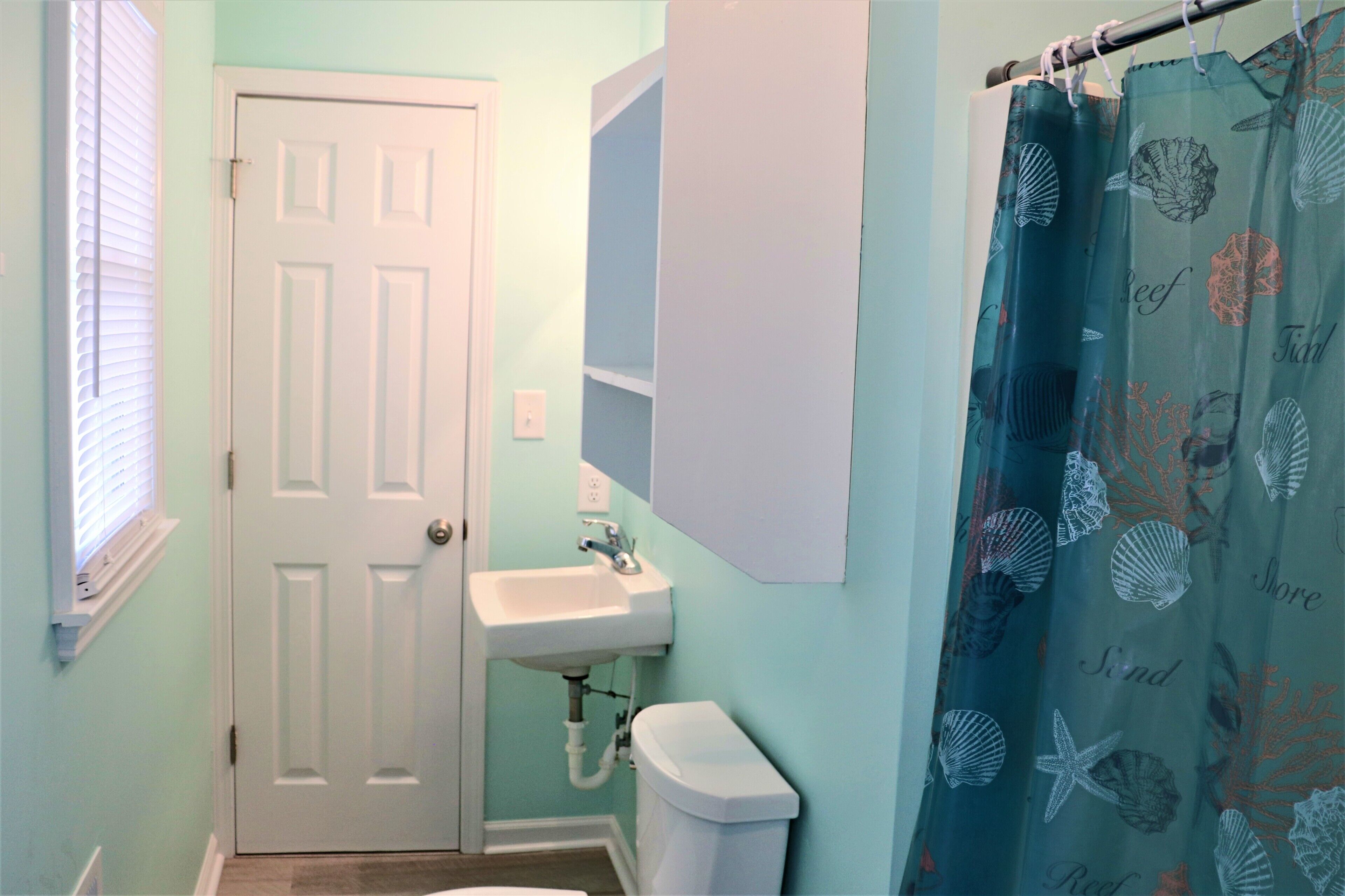 A bathroom with a white door, a sink, and a toilet.