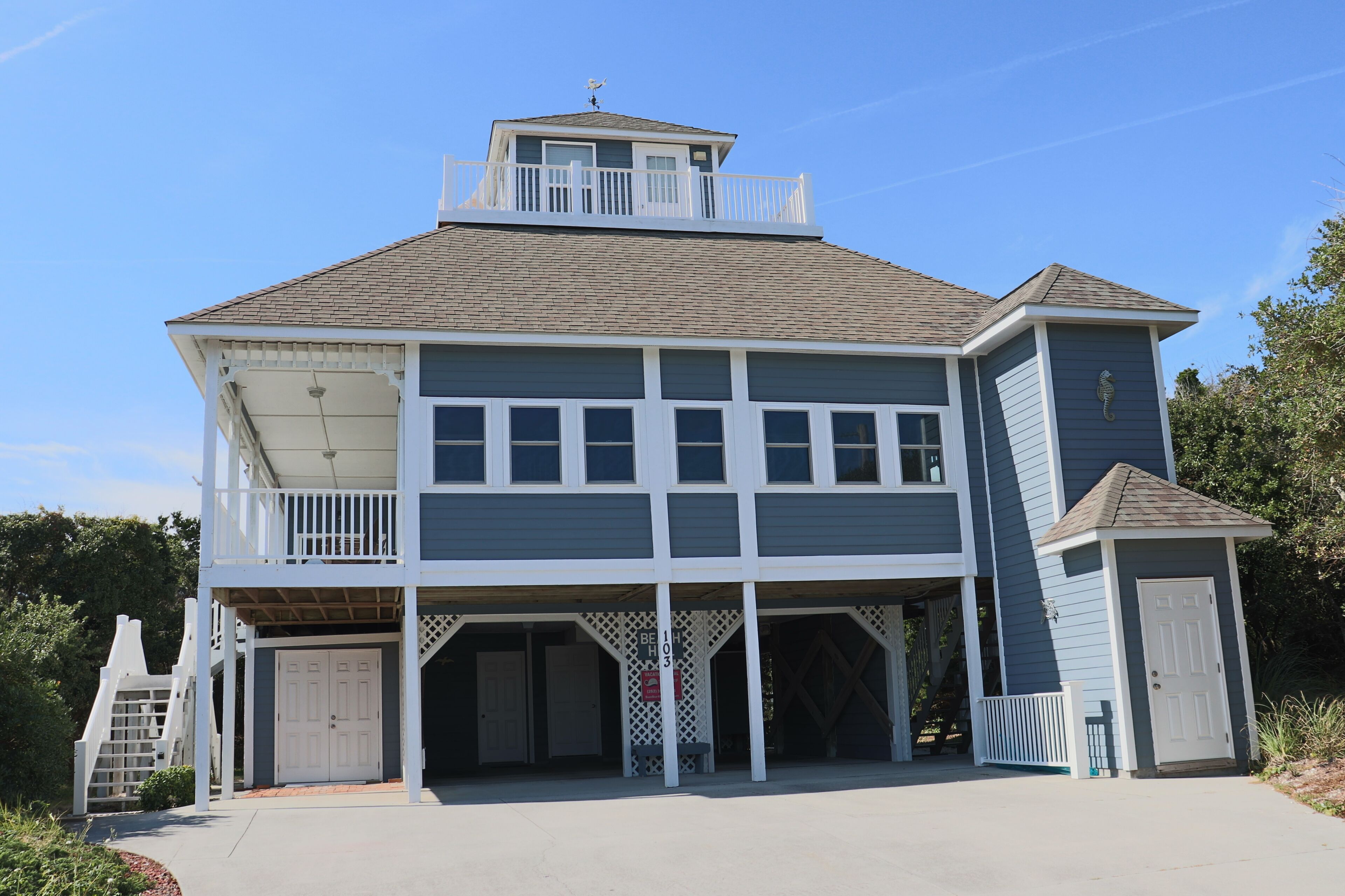 A two-story building with a balcony, a garage, and a small attached structure.