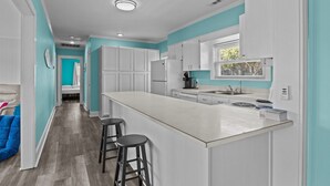 Une cuisine moderne avec des meubles blancs, un grand îlot central et des tabourets de bar.