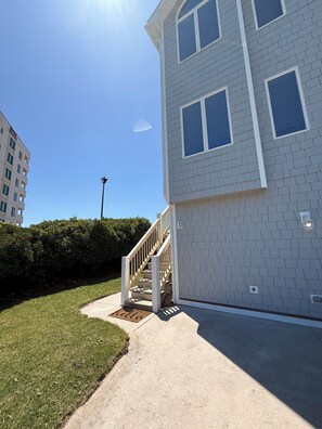 Un edificio residenziale con una scalinata che conduce all'ingresso, un prato curato e un cielo sereno.