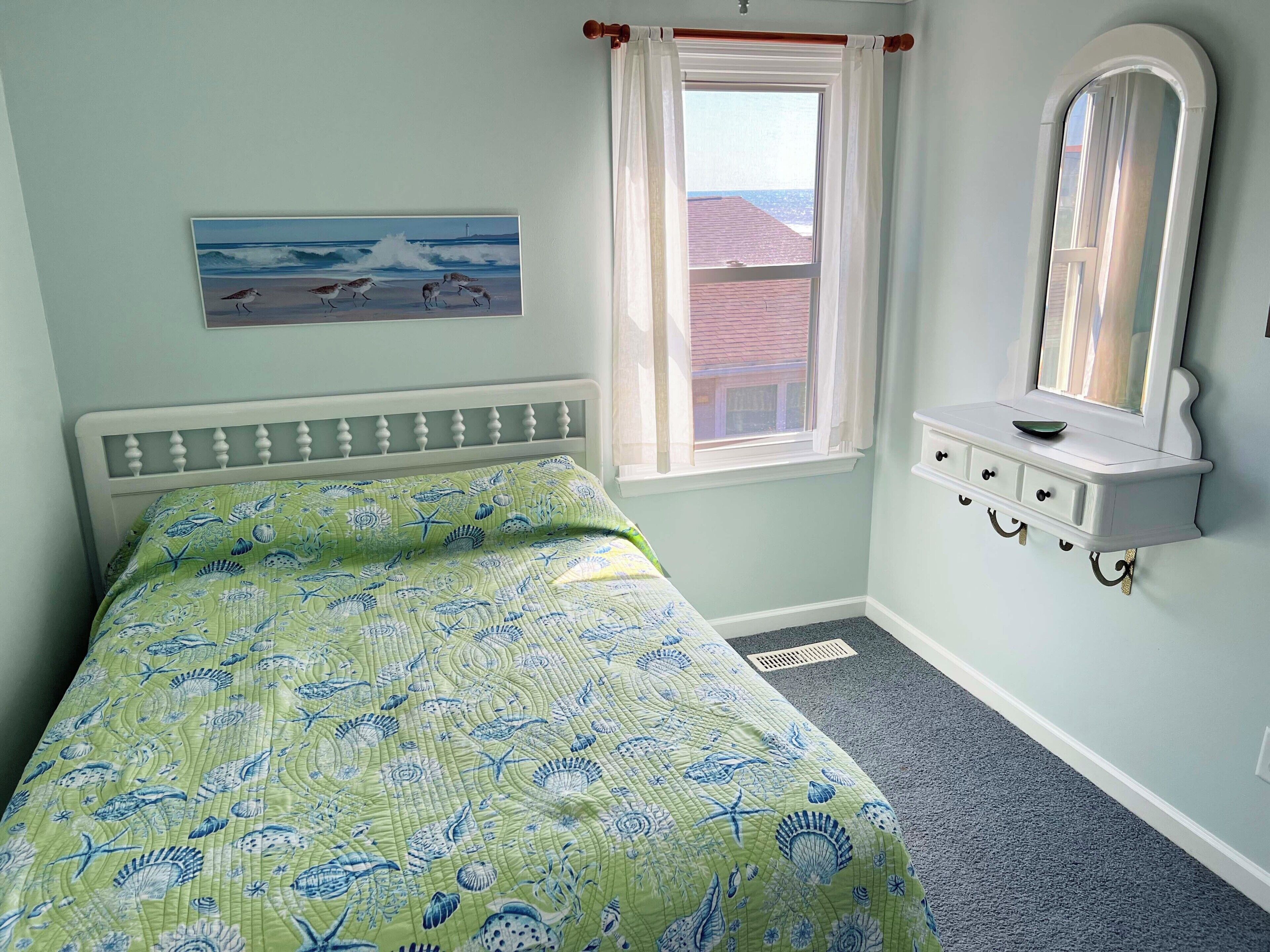 Une chambre à coucher avec un lit, une fenêtre, un tableau et une commode.