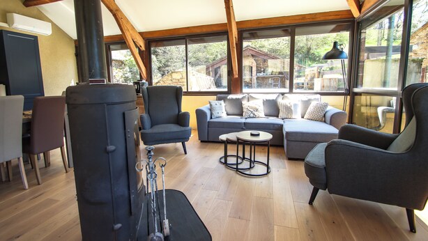 A spacious living area with a large window, a sofa set, and a fireplace. - Cosy country side property with three cottages and covered swimming pool (Centres)