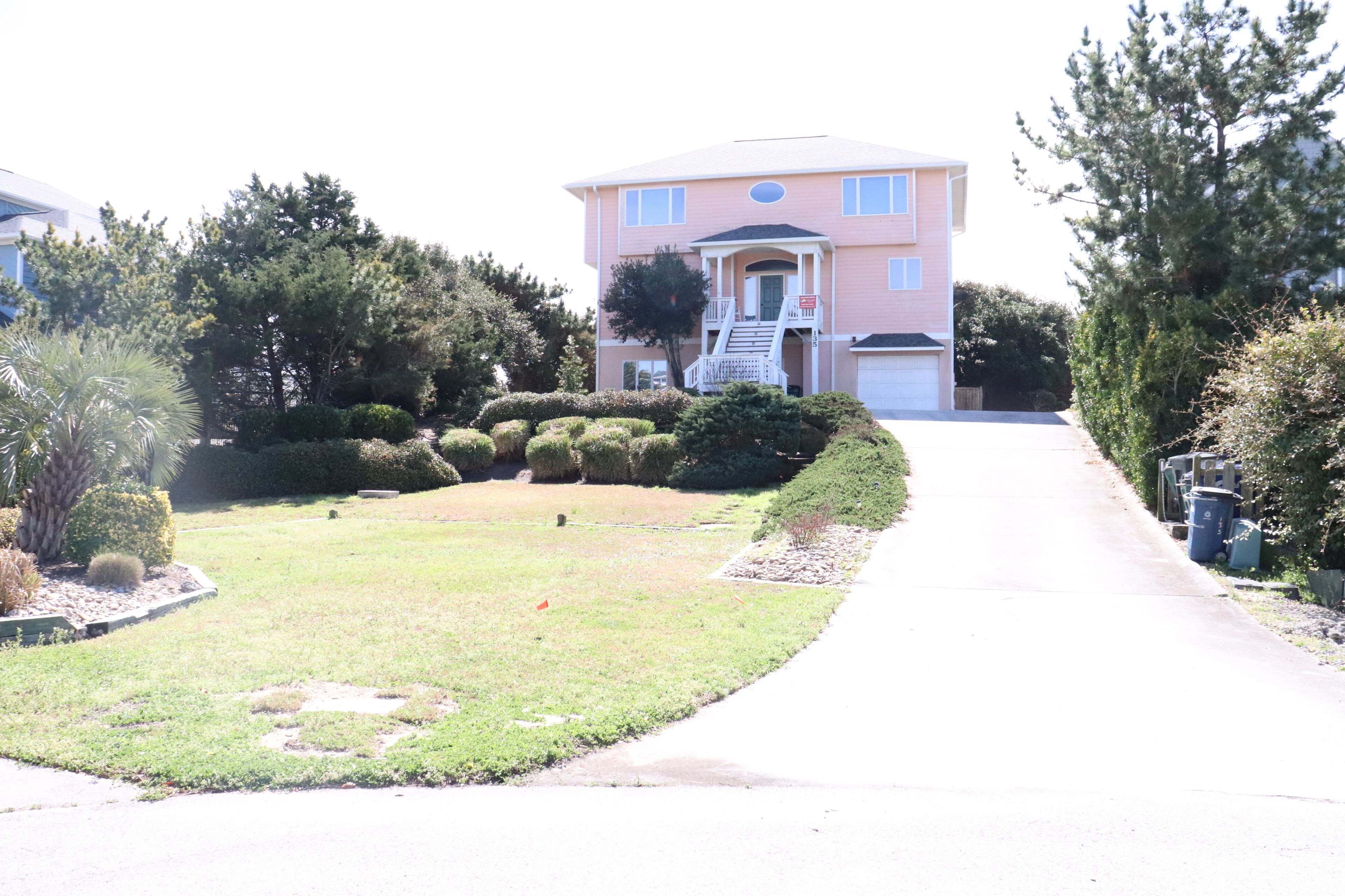 A two-story residential building with a front porch, a driveway, and well-maintained landscaping.