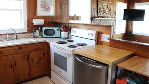 Una cocina con armarios de madera, estufa, microondas y refrigerador.