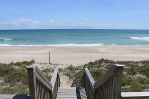 Ein hölzerner Steg führt zu einem Strand mit freiem Blick auf das Meer.