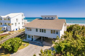 A white multi-story building with a flat roof, a covered parking area, and a view of the ocean. - Oceanfront 4BR with Views & Private Beach Access (Emerald Isle)