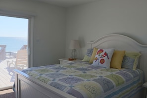 Ein Schlafzimmer mit Bett, Nachttisch, Lampe und Meerblick.