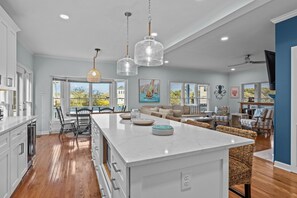 A spacious kitchen with a large island, wooden flooring, and pendant lighting. - Family Retreat with Hot Tub & Game Room and Short Walk to Beach (Emerald Isle)
