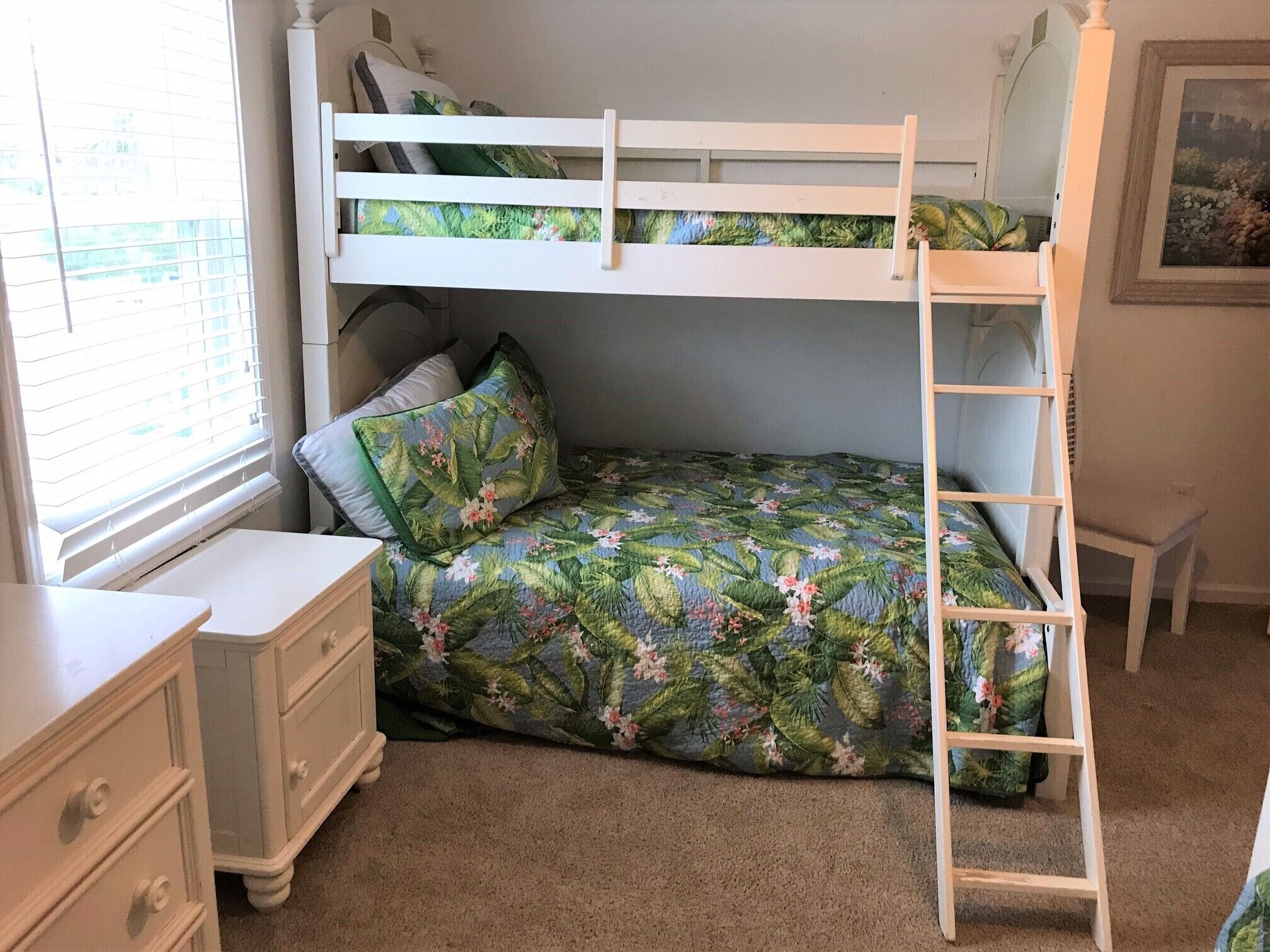 A bunk bed with a ladder, a nightstand, a dresser, and a window with blinds.