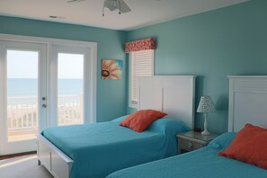 A room with two beds, a window with a view, a ceiling fan, and a painting on the wall. - Multi‑Level Beach Home w/ Decks & Walkway to Sand (Emerald Isle)