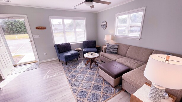 A living room with a ceiling fan, two sofas, a coffee table, and a rug.