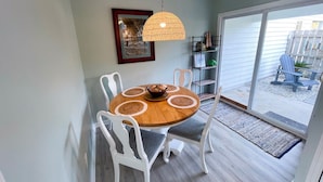 A dining area with a wooden table, white chairs, and a hanging light fixture.
