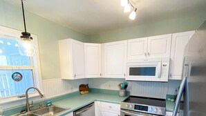 A modern kitchen with white cabinets, stainless steel appliances, and a blue countertop.
