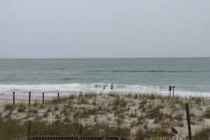 A beach with a wooden fence, grassy dunes, and the ocean. - Ocean Front Beach Home 4BR – Views, Decks & Beach Access (Emerald Isle)