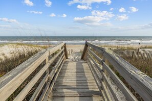 A wooden boardwalk leading to a beach with a clear sky. - Pool| Close to Beach| Sleeps 10 (Emerald Isle)