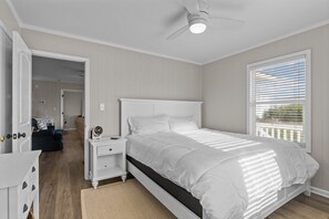 A bedroom with a bed, a nightstand, a dresser, a ceiling fan, and a window with blinds. - Pool| Close to Beach| Sleeps 10 (Emerald Isle)