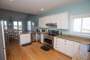 A kitchen with white cabinets, a stainless steel oven, and a granite countertop. - Soul Shine, Ocean & Sound Retreat - POOL & Hot Tub (Emerald Isle)