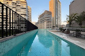 Piscina no terraço com vista para edifícios altos ao redor.