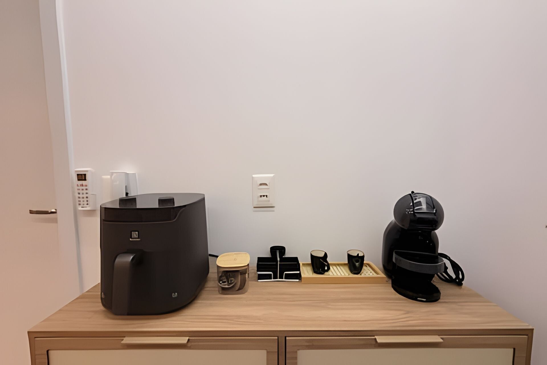 Una zona de cocina con cafetera, hervidor y máquina de café sobre una encimera de madera.