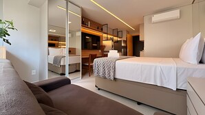 Et moderne hotelværelse med seng, sofa, skrivebord og tekøkken.