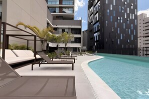 A modern poolside area with lounge chairs and a swimming pool. - Condomínio Helbor Edition  (São Paulo)