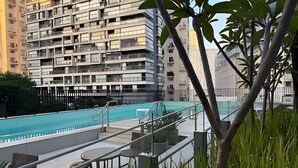 En boligbygning med swimmingpool, udendørs siddepladser og udsigt til omkringliggende højhuse.