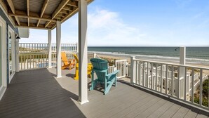 A wooden deck with a view of the ocean, a covered area with chairs, and a white railing. - Dog-friendly 5BR Beach Home with Pool & Ocean Views (Emerald Isle)