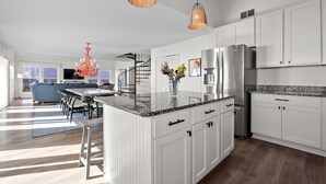 A modern kitchen with white cabinetry, a granite countertop, and stainless steel appliances. - Dog-friendly 5BR Beach Home with Pool & Ocean Views (Emerald Isle)
